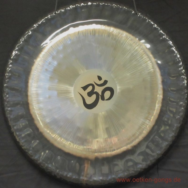 Circular gong with a metallic surface and an "Om" symbol in the centre.