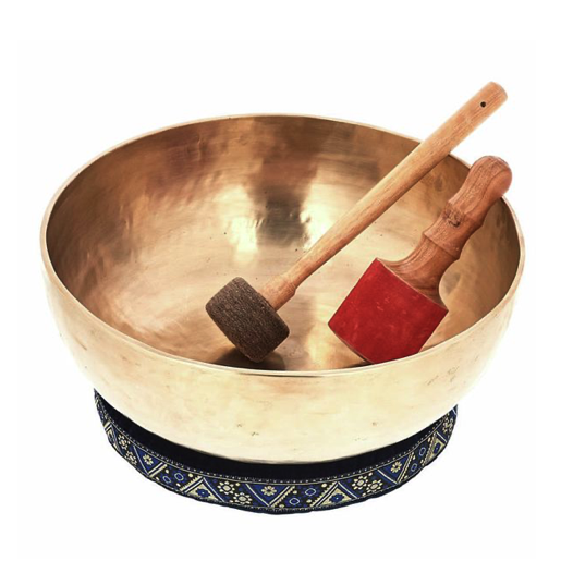 Set of brass singing bowls arranged with a box and two mallets, alongside small plants.