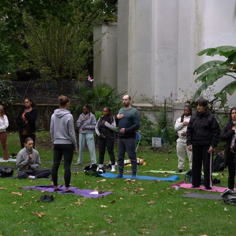 A diverse group of people participating in an outdoor yoga session on mats.